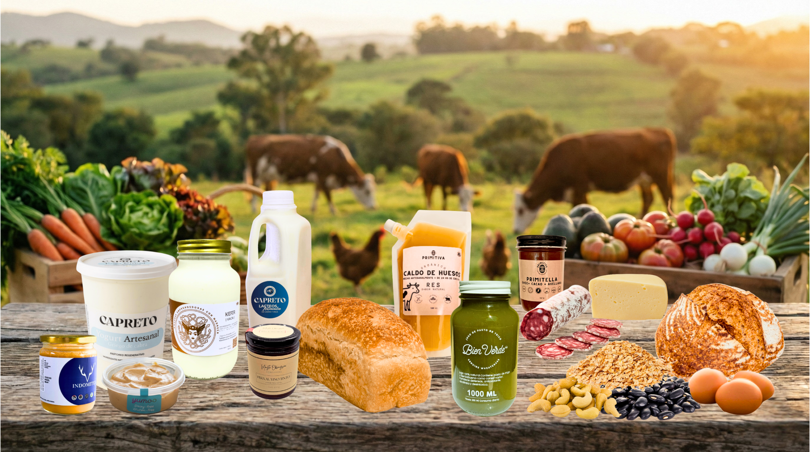 Mesa de madera con alimentos artesanales de La Comuna frente a un rancho con vacas y gallinas en pastoreo